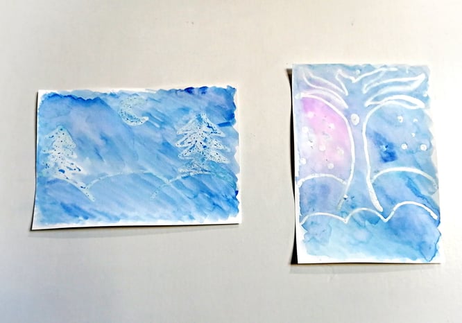 Two glue resist winter scenery paintings on a wall