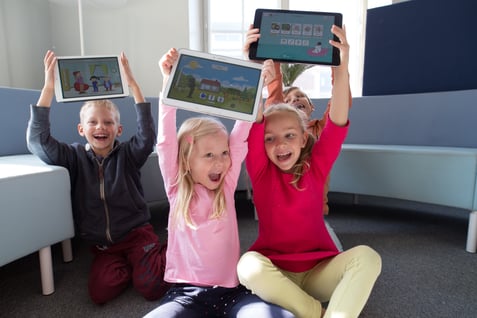 Three kids holding tablets and smiling