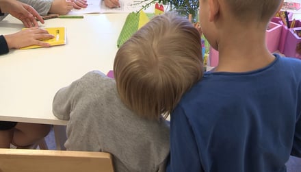A child leaning on another child's shoulder during a Moomin Language School playful lesson