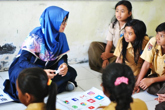 Children and teacher sit in a circle on the floor